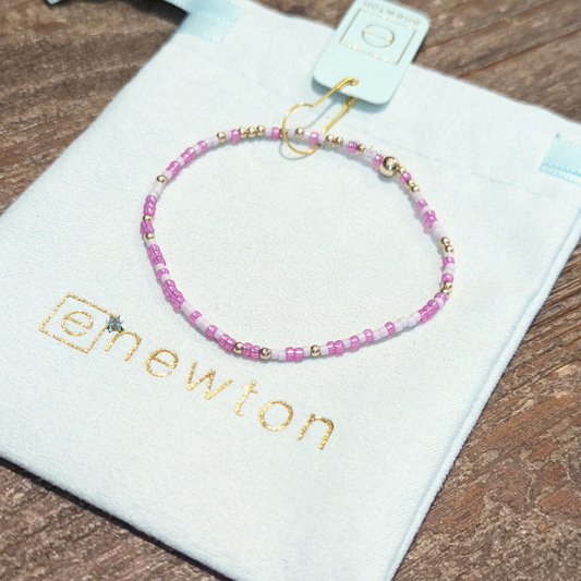 Hope Unwritten Bracelet - Caught in A Pinkle by eNewton. Made with 2mm pink mix seed beads and 2mm 14k gold-filled beads. Measures standard 6.25" hand beaded on high performance elastic, worry-free wear‚ sleep, shower and sweat in it. Stacks well with all bracelets. Shop at The Painted Cottage in Edgewater, MD.