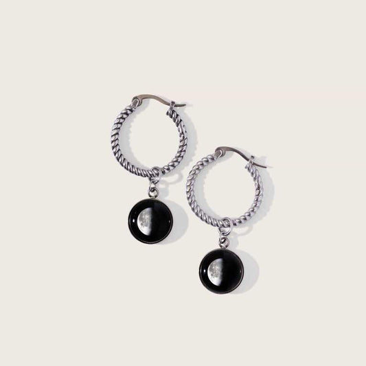 Moonglow Carina Hoop earrings features two 10mm moon images on 20mm stainless steel hoops with snap-down bar closure. Boasts two unique moon phases based on your special date. Shop at The Painted Cottage in Edgewater, MD.