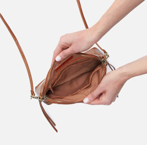 The Reeva crossbody in truffle brown by HOBO is perfect for everything from mornings at the coffeeshop to happy hour with friends. Adjust the strap to wear as a crossbody, short shoulder or wristlet for three looks in one! Crafted in our Vintage Hide leather that only gets more beautiful over time with use and wear. Check it out at the Painted Cottage in Edgewater, MD
