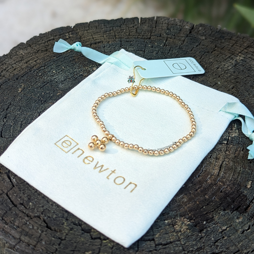 Classic Gold 3mm Bracelet - 4mm Signature Cross Charm by eNewton. Made with 3mm 14kt gold-filled beads and signature cross charm. Shop at The Painted Cottage in Edgewater, MD.