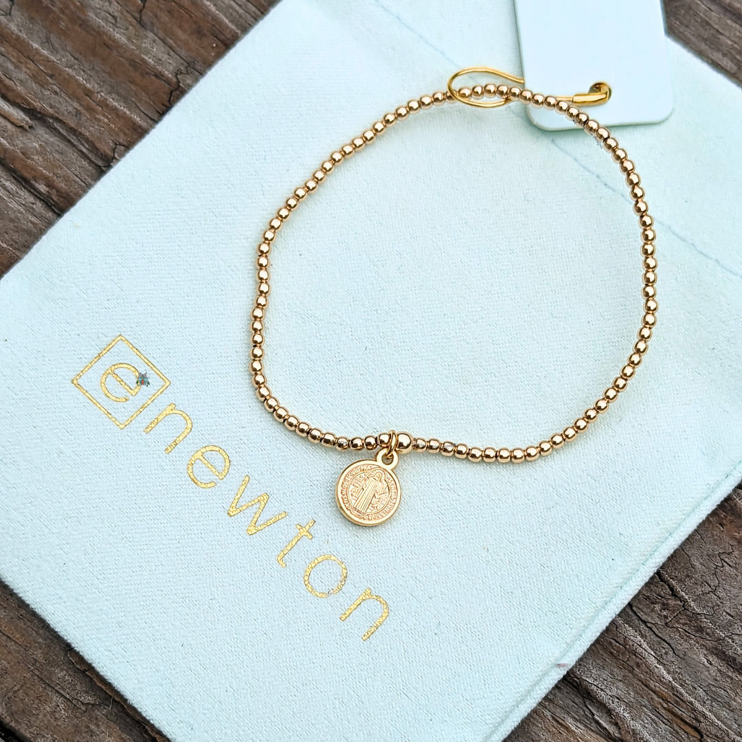 Classic Gold 2mm Bracelet Blessing Small Gold Disc by eNewton. Made with 2mm 14kt gold-filled beads and our 8mm blessing small disc of St. Benedict. Shop at The Painted Cottage in Edgewater, MD.