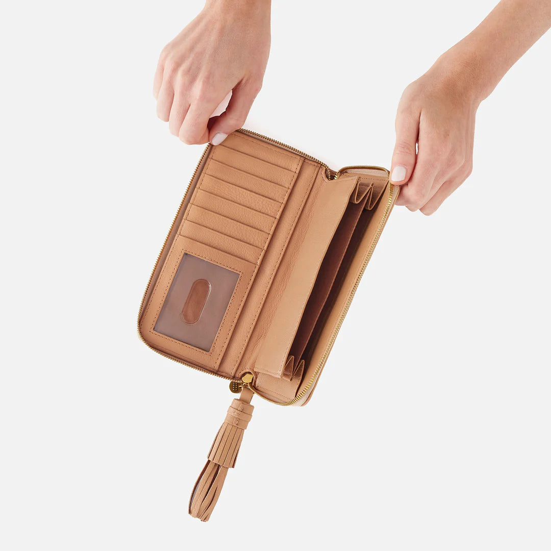 The Nila Large Zip Around Wallet in sandstorm is a continental design with interior organization for your cash and cards and a leather tassel zipper for added style and functionality. Available at the Painted Cottage in Edgewater, MD