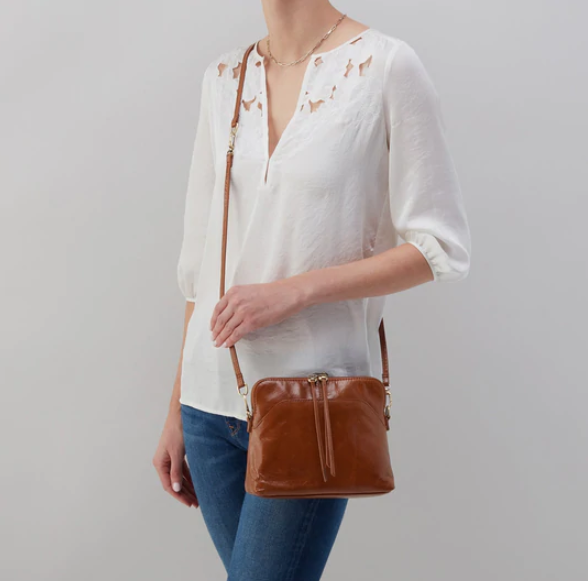 The Reeva crossbody in truffle brown by HOBO is perfect for everything from mornings at the coffeeshop to happy hour with friends. Adjust the strap to wear as a crossbody, short shoulder or wristlet for three looks in one! Crafted in our Vintage Hide leather that only gets more beautiful over time with use and wear. Check it out at the Painted Cottage in Edgewater, MD